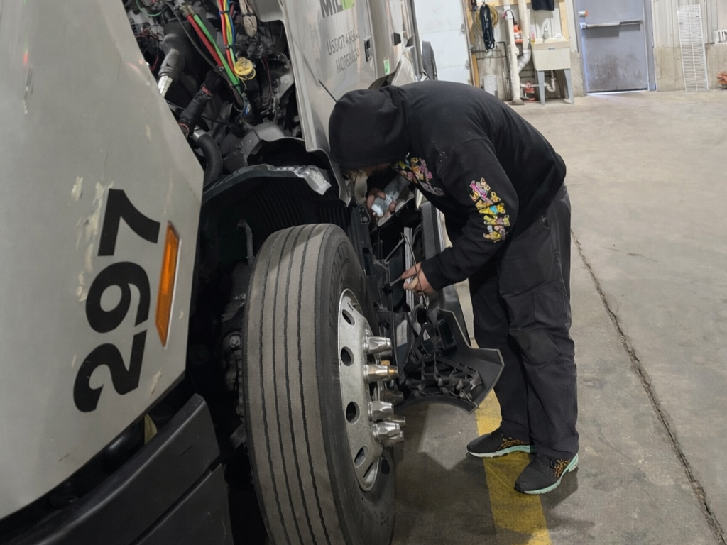 Miliva mechanic servicing the front of a truck cab inside the in-house shop
