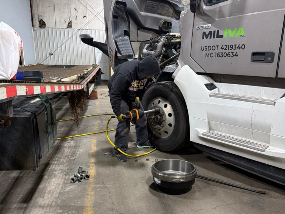 Miliva technician changing a wheel on a Volvo VNL 860 in the repair facility